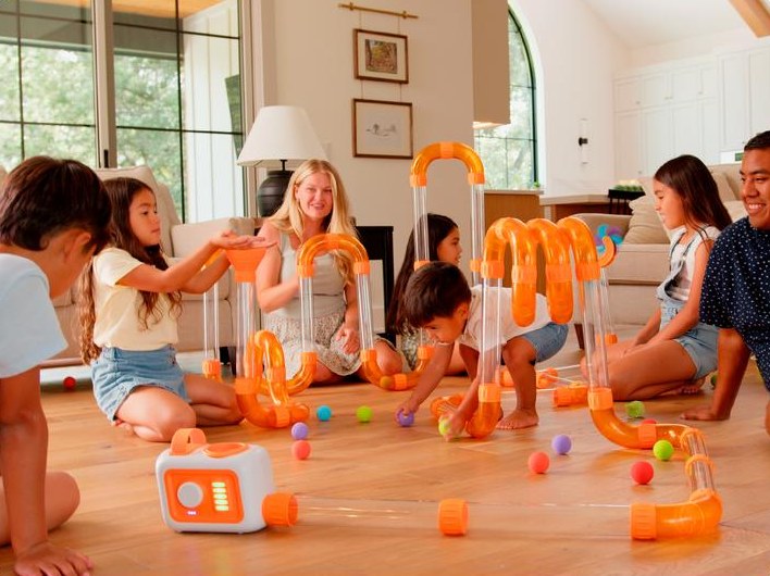 Kids and parents on the living room floor building a giant Tube Tinkers track