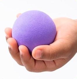 A child's hand holding a large purple foam ball