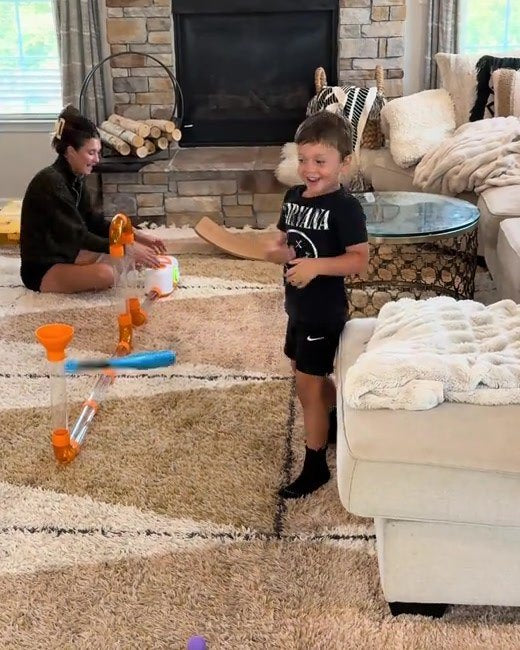 A boy hitting foam balls with a toy bat as they launch from an Tube Tinkers tube