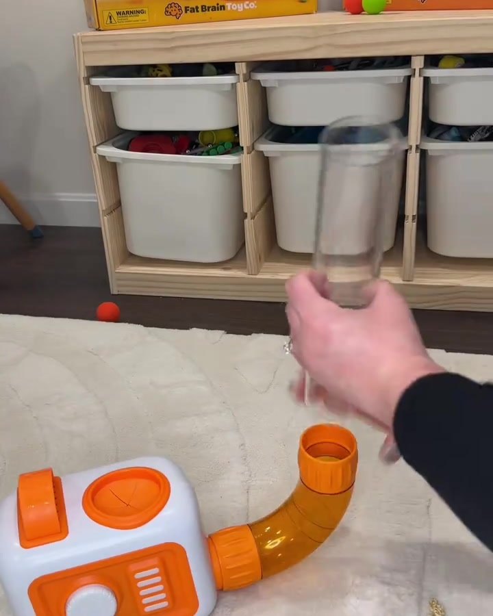 A hand pushing a clear tube into an orange corner piece